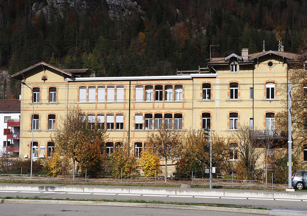 Bâtiment d'usine d'horlogerie dans la rue de l'École d'horlogerie à Fleurier, photographie de 2025.