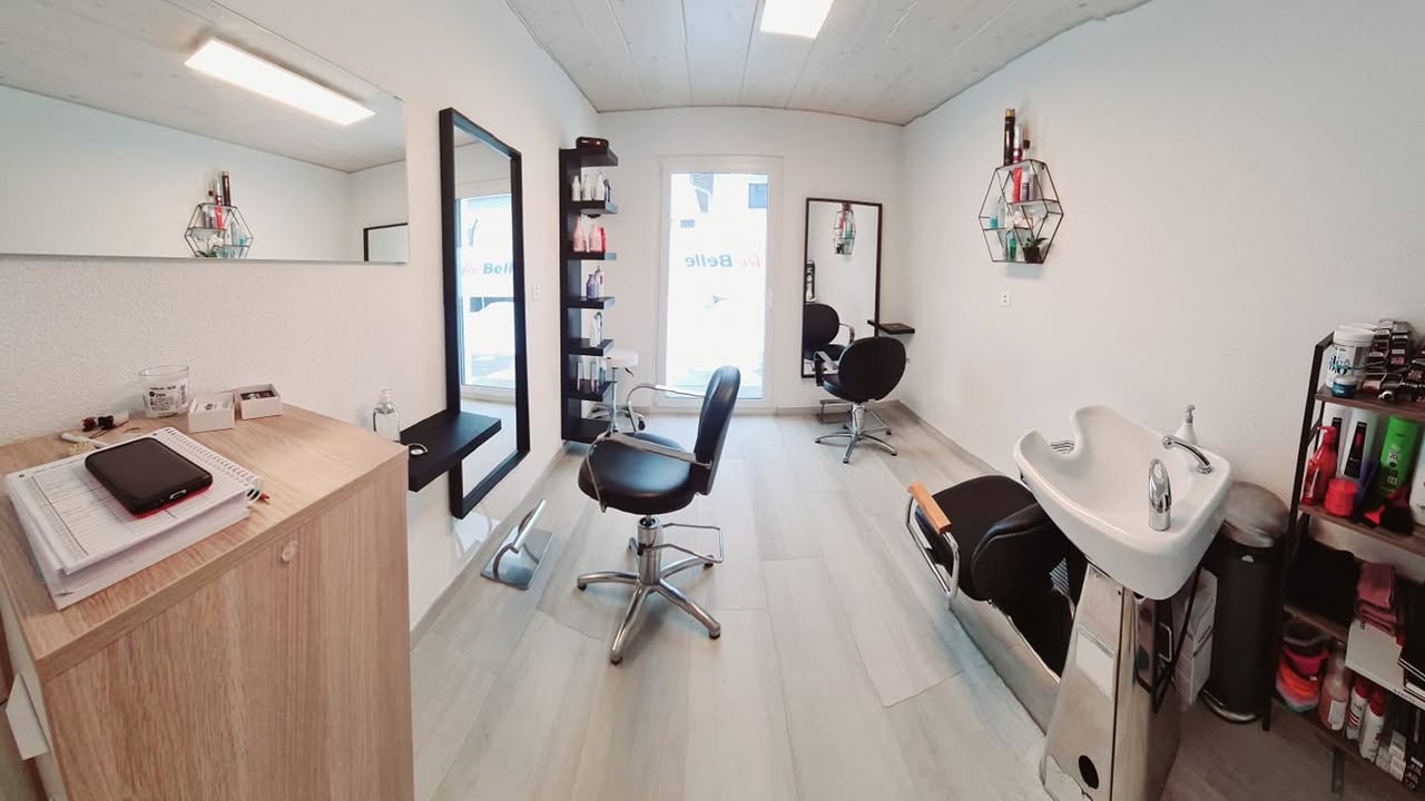 Intérieur du salon Re’Belle Coiffure à Couvet : fauteuils, miroirs et bac à shampooing.